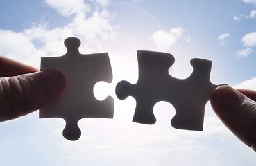 Image showing Hands trying to fit two puzzle pieces together