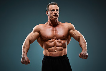 Image showing torso of attractive male body builder on gray background.