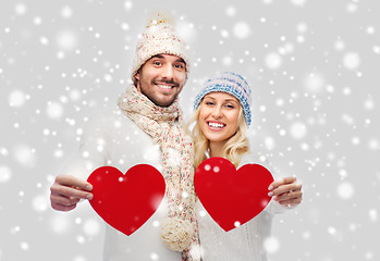 Image showing smiling couple in winter clothes with red hearts