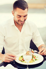 Image showing happy man eating salad for dinner at restaurant