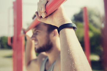 Image showing young man exercising on horizontal bar outdoors