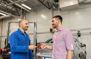 Image showing auto mechanic giving key to man at car shop