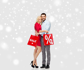 Image showing happy couple with red shopping bags over snow