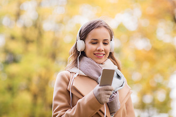 Image showing woman with smartphone and earphones in autumn park