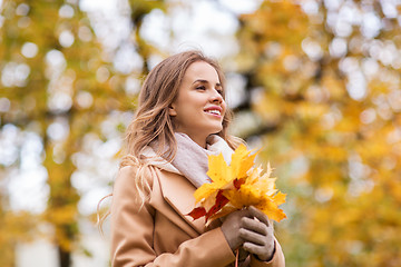 Image showing beautiful woman with maple leaves in autumn park