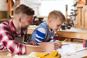 Image showing happy father and son with blueprint at workshop