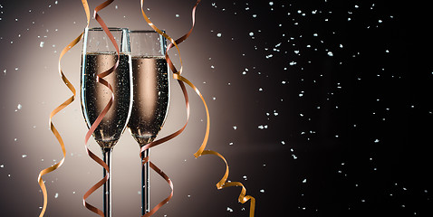 Image showing Glasses with fizzing champagne, decorative ribbons and snow flakes closeup