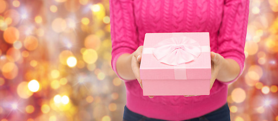 Image showing close up of woman in pink sweater holding gift box