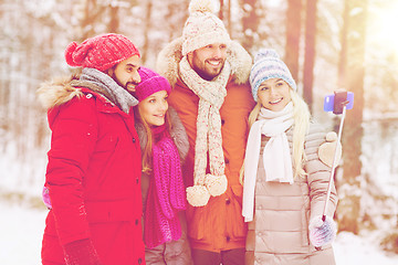 Image showing smiling friends with smartphone in winter forest