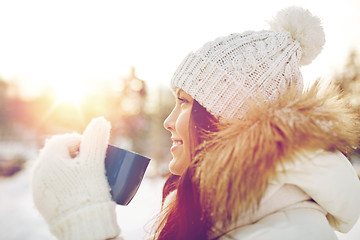 Image showing happy young woman with tea cup outdoors in winter