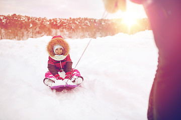Image showing parent carrying happy little kid on sled in winter