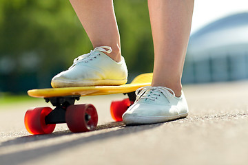 Image showing close up of female feet riding short skateboard