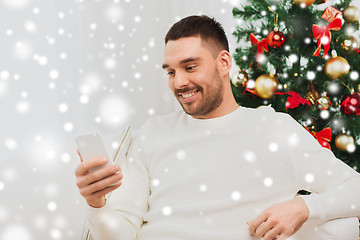 Image showing smiling man with smartphone at home for christmas