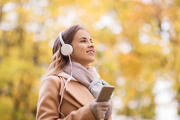 Image showing woman with smartphone and earphones in autumn park