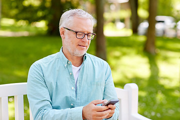 Image showing happy senior man texting on smartphone at summer