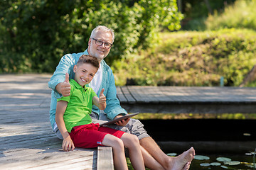 Image showing grandfather and boy with tablet pc on river berth