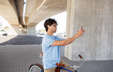 Image showing man with smartphone and earphones on bicycle