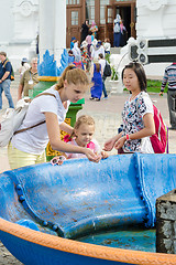 Image showing Sergiev Posad - August 10, 2015: She visitor Holy Trinity St. Sergius Lavra washes the baby\'s face with holy water at the canopy over the cup with a cross