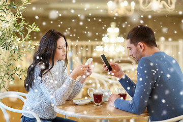 Image showing couple with smartphones drinking tea at cafe