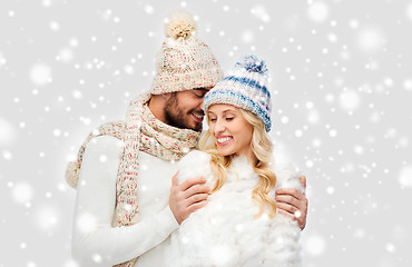 Image showing smiling couple in winter clothes hugging over snow