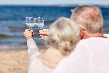 Image showing happy senior couple drinking wine on summer beach