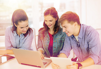 Image showing three smiling students with laptop and tablet pc