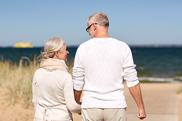 Image showing happy senior couple holding hands on summer beach