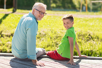 Image showing grandfather and grandson sitting on river berth