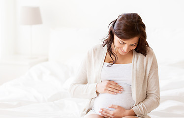 Image showing happy pregnant woman sitting on bed at home