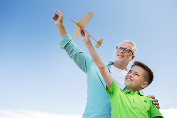 Image showing senior man and boy with toy airplane over sky
