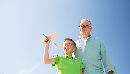 Image showing senior man and boy with toy airplane over sky