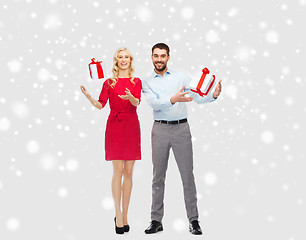 Image showing happy couple with christmas gift boxes over snow