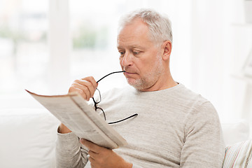 Image showing senior man in glasses reading newspaper at home