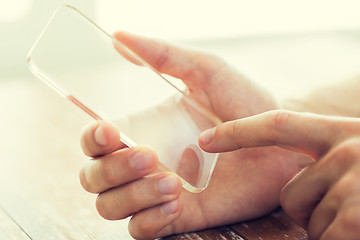 Image showing close up of male hand with transparent smartphone