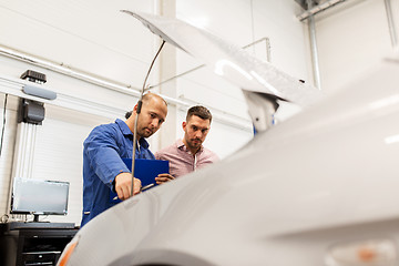 Image showing auto mechanic with clipboard and man at car shop