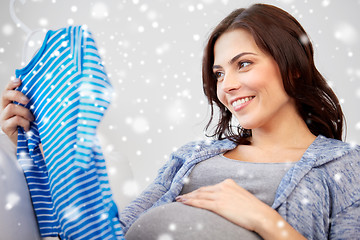 Image showing happy woman holding baby boys bodysuit at home