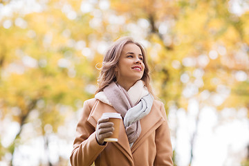 Image showing happy young woman drinking coffee in autumn park