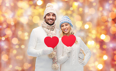 Image showing smiling couple in winter clothes with red hearts