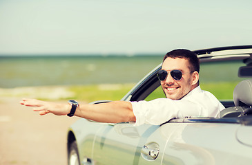 Image showing happy man driving cabriolet car and waving hand