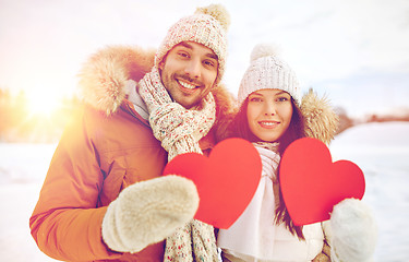 Image showing happy couple with red hearts over winter landscape