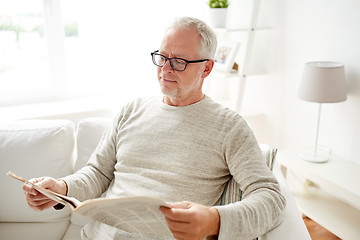 Image showing senior man in glasses reading newspaper at home