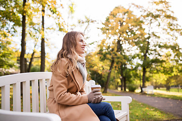 Image showing happy young woman drinking coffee in autumn park