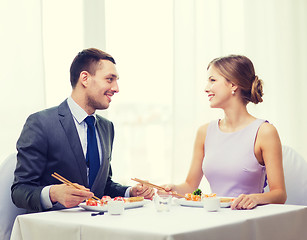 Image showing smiling couple eating sushi at restaurant