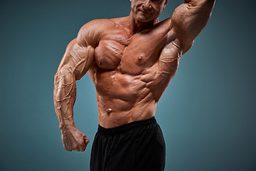 Image showing torso of attractive male body builder on gray background.