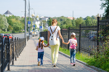 Image showing Mother and two daughters are on the sidewalk along the road