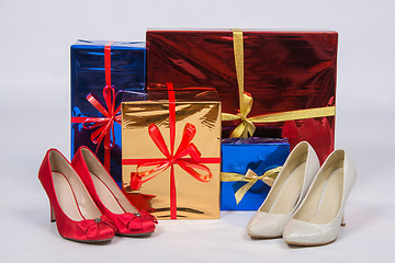 Image showing Red and white female shoes with high heels, standing near boxes with gifts