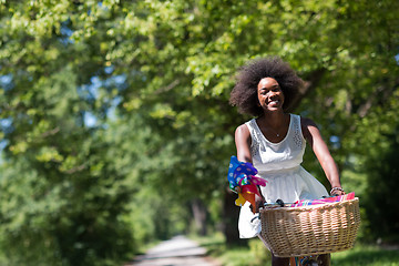 Image showing pretty young african american woman riding a bike in forest