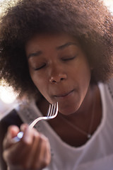 Image showing a young African American woman eating pasta