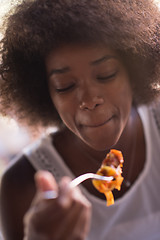 Image showing a young African American woman eating pasta