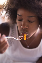 Image showing a young African American woman eating pasta